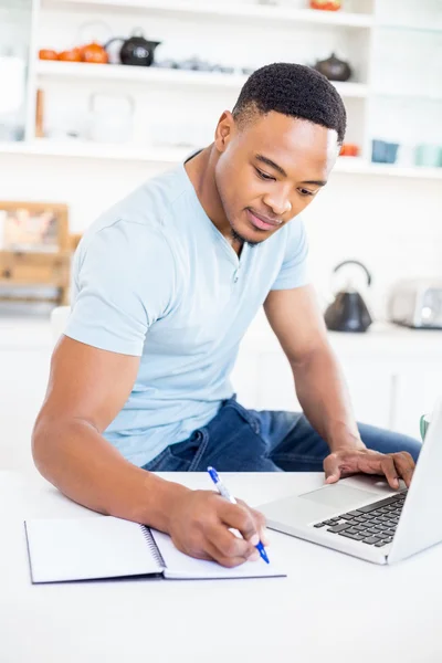 Man met laptop tijdens het schrijven in dagboek — Stockfoto