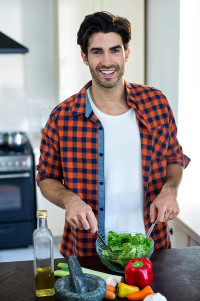 Hombre mezcla ensalada en la cocina —  Fotos de Stock