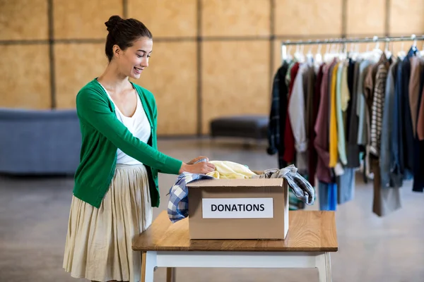 Mulher classificando roupas de caixa de doação — Fotografia de Stock
