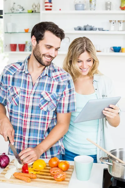 Casal cortando vegetais usando tablet — Fotografia de Stock