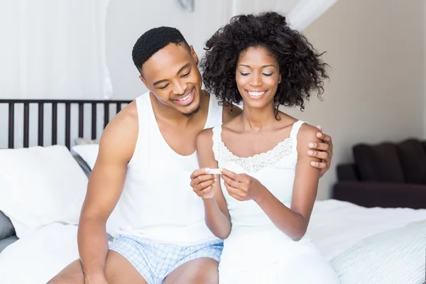 Casal olhando para o teste de gravidez na cama — Fotografia de Stock