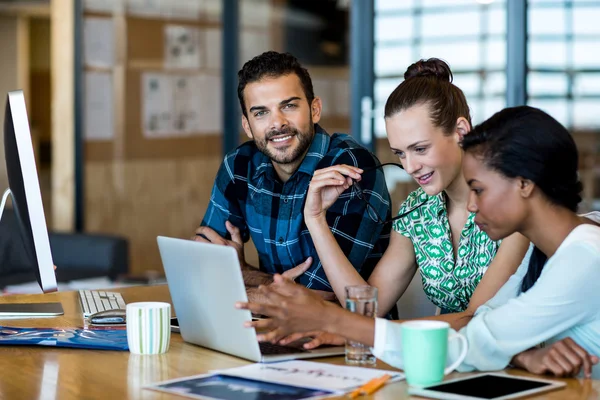 Hombres y mujeres sentados en el escritorio — Foto de Stock