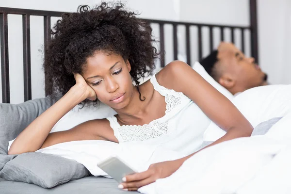 Donna utilizzando telefono uomo dormire — Foto Stock