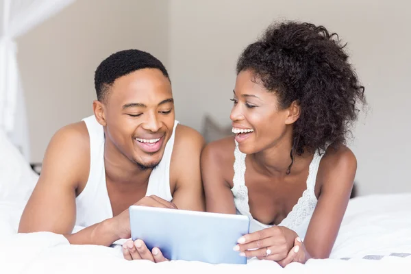 Casal deitado na cama e usando tablet — Fotografia de Stock