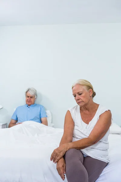 Sad senior couple sitting on bed — Stock Photo, Image
