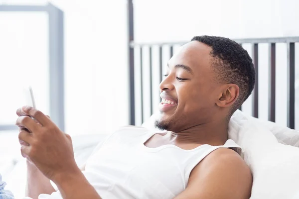 Man met mobiele telefoon op bed — Stockfoto