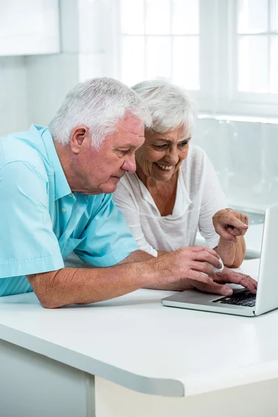 Äldre par med laptop i tabell — Stockfoto