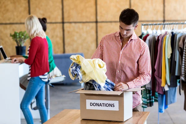 Hombre clasificando la ropa de la caja de donación —  Fotos de Stock