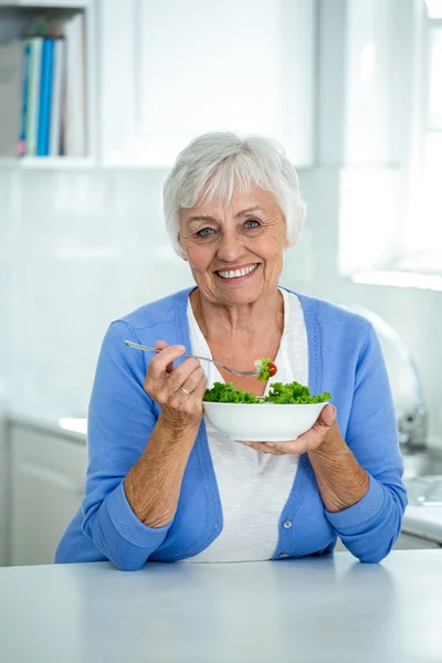 Seniorin isst Salat in Küche — Stockfoto