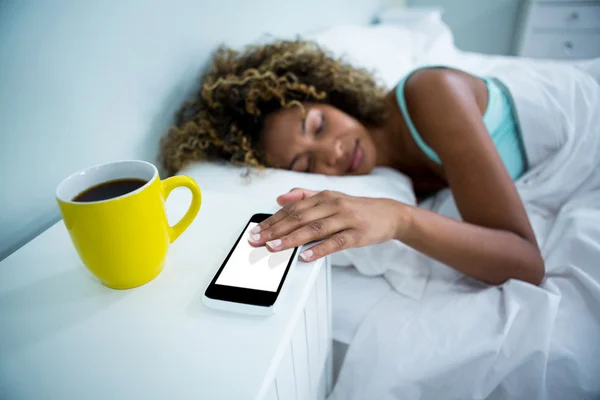 Женщина трогает телефон во время сна — стоковое фото