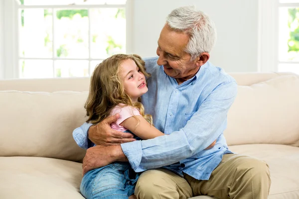Улыбающийся дедушка обнимает девушку — стоковое фото