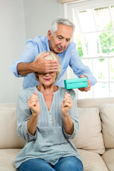 Senior man gifting woman at home — Stock Photo, Image