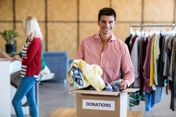 Hombre clasificando la ropa de la caja de donación —  Fotos de Stock