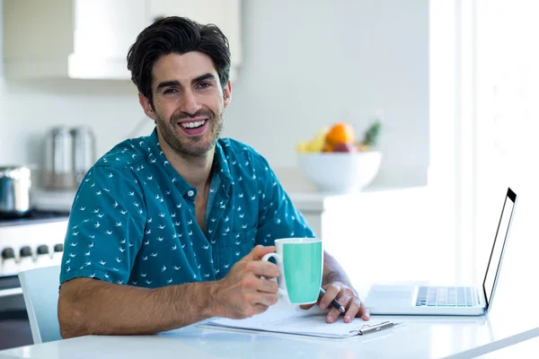 Man having coffee while writing on clipboard — Stock Photo, Image