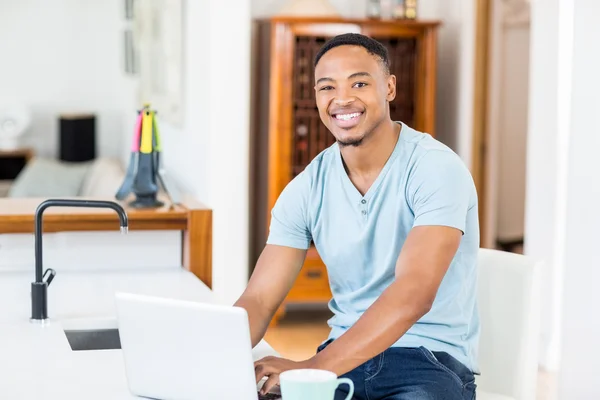 Junger Mann benutzt Laptop in Küche — Stockfoto