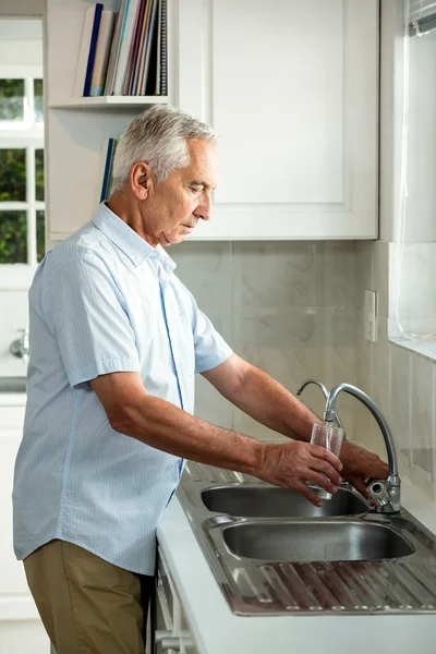 Äldre man fylla vatten i glas — Stockfoto