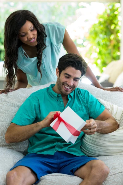 Женщина смотрит, как мужчина разворачивает подарок — стоковое фото