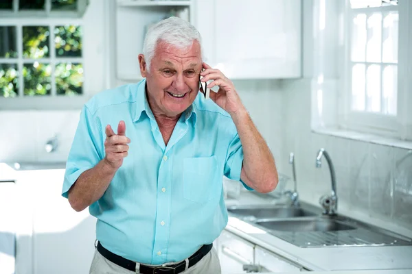 Мужчина разговаривает по телефону на кухне — стоковое фото