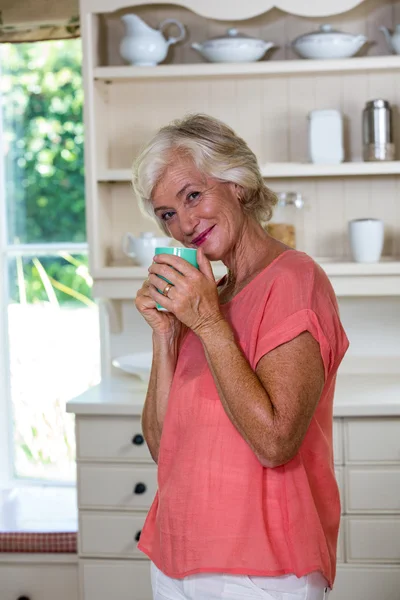 Старша жінка має каву на кухні — стокове фото