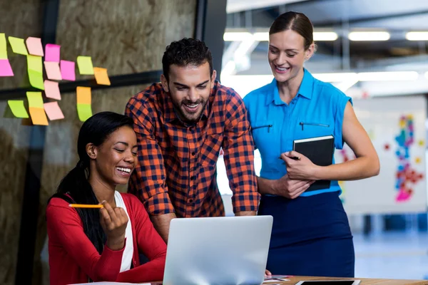 Collega's communiceren met behulp van laptop aan balie — Stockfoto