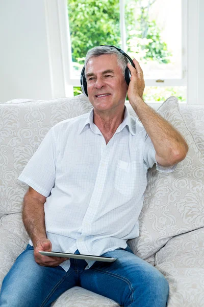 Senior man listening music in sitting room — стоковое фото