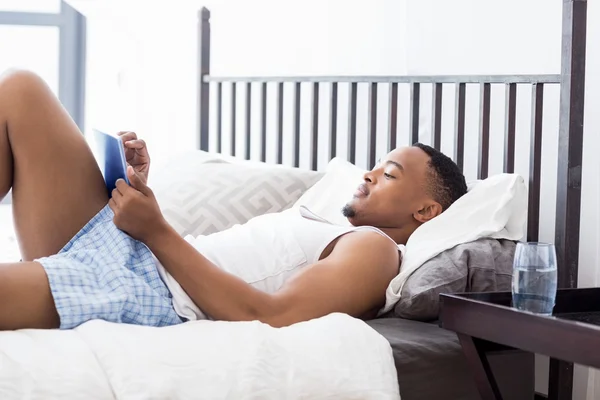 Junger Mann mit Tablette im Bett — Stockfoto