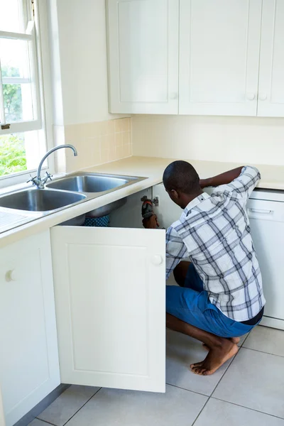 Человек чинит раковину на кухне — стоковое фото