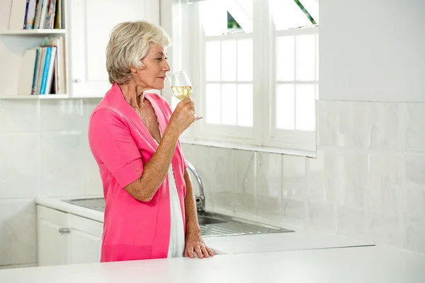 Mujer mayor sosteniendo vino blanco — Foto de Stock