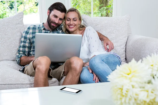 Casal usando laptop no sofá — Fotografia de Stock