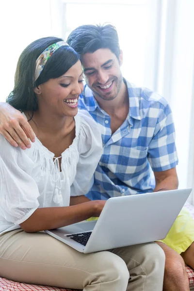 Paret sitter på sängen med laptop — Stockfoto