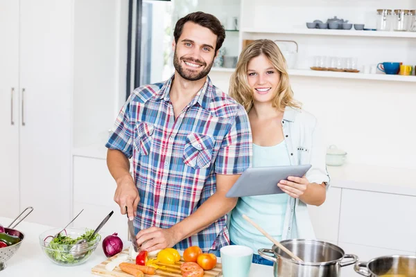 Couple chopping vegetable holding tablet — Stock Photo, Image