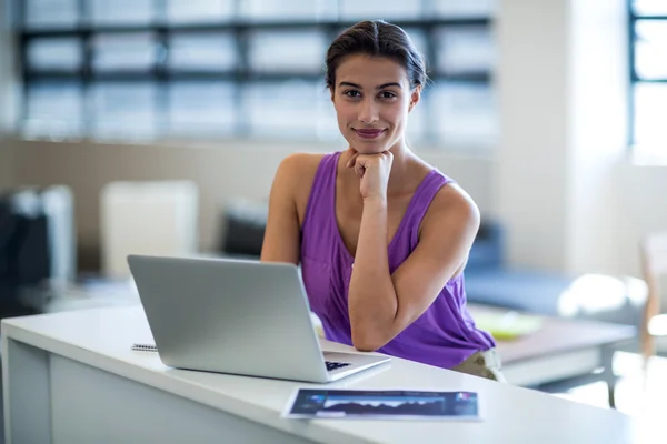 Kobieta siedzi przy biurku przy użyciu laptopa — Zdjęcie stockowe