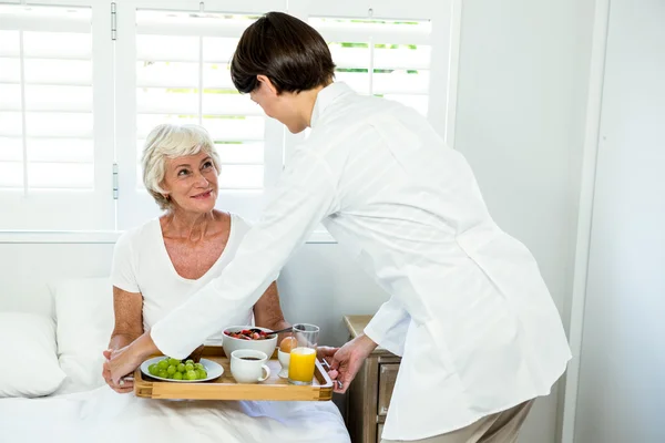Caregiver serving breakfast to woman — Stock Photo, Image