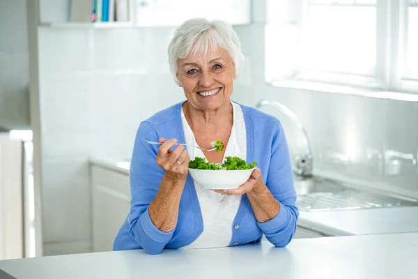 Äldre kvinna med sallad i kök — Stockfoto