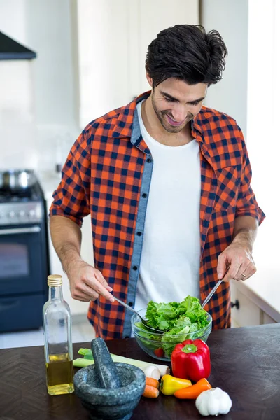 Человек смешивания салат на кухне — стоковое фото