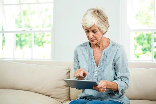 Mulher idosa usando tablet no sofá — Fotografia de Stock
