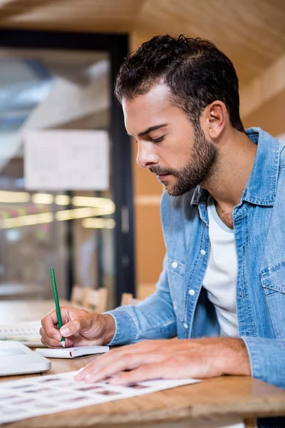 Man in office writing in notepad — Stock Photo, Image