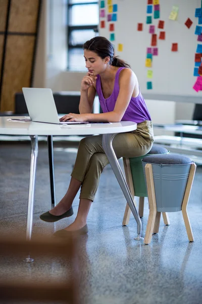 女人坐在办公桌前使用笔记本电脑 — 图库照片