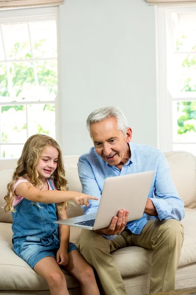 Chica señalando al ordenador portátil con el abuelo — Foto de Stock