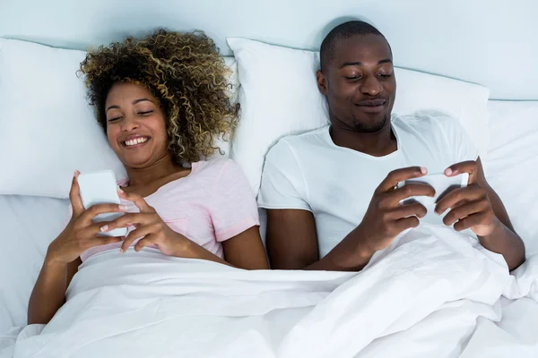 Couple utilisant le téléphone sur le lit — Photo