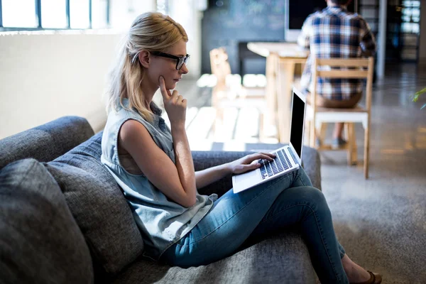 Vrouw zittend op de bank met laptop — Stockfoto