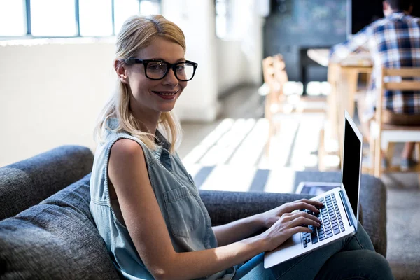 Mulher sentada no sofá usando laptop — Fotografia de Stock