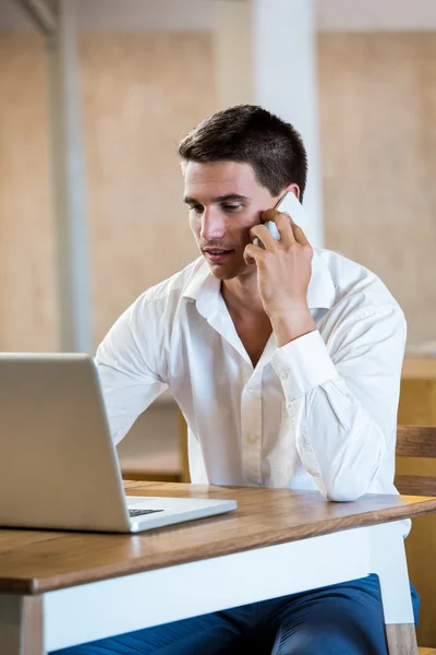 Man talking on phone using laptop — Stock Photo, Image