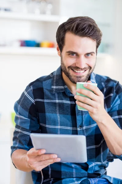 Mężczyzna stosujący tabletkę podczas picia kawy — Zdjęcie stockowe
