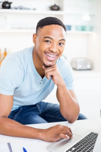 Junger Mann benutzt Laptop in Küche — Stockfoto