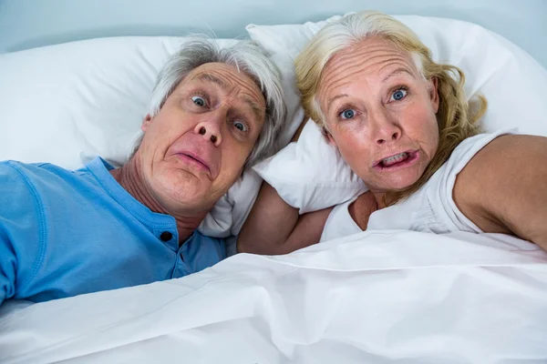 Pensionerat par att göra ansikten på sängen — Stockfoto