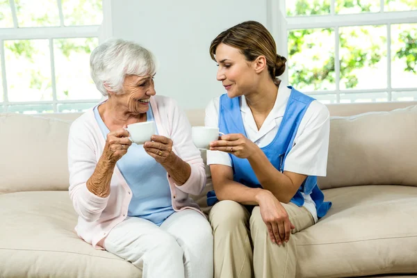 Enfermera y mujer sosteniendo tazas de café — Foto de Stock