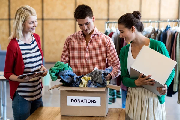 Kollegen sortieren Kleidung aus Spendenbox — Stockfoto