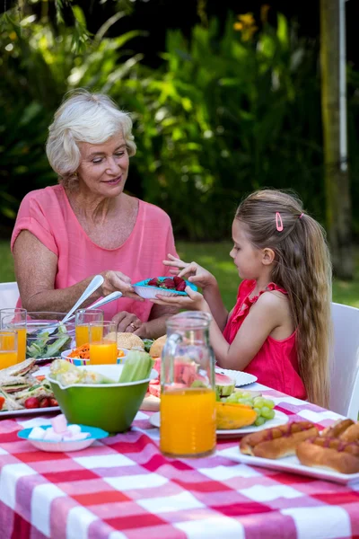 Abuela sirviendo comida a su nieta —  Fotos de Stock