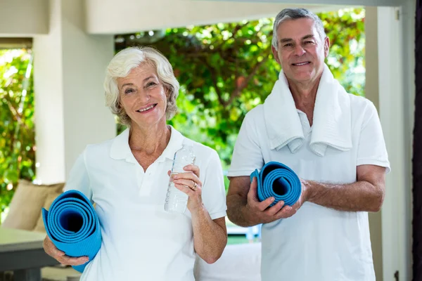 Senior couple holding exercise mats — Stock Photo, Image